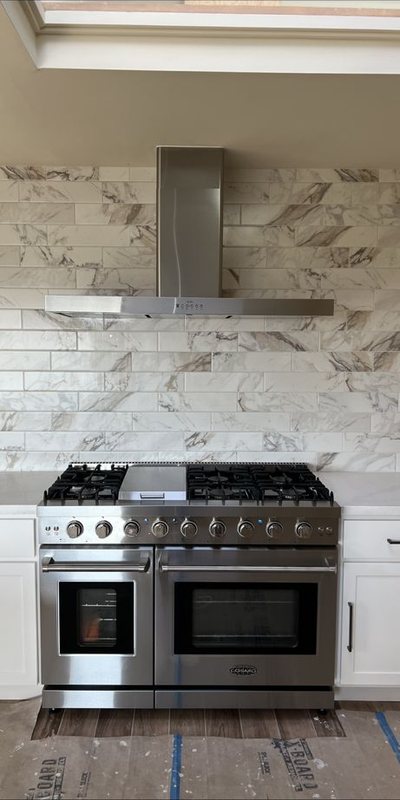 Range and vent hood installation against a marble backsplash